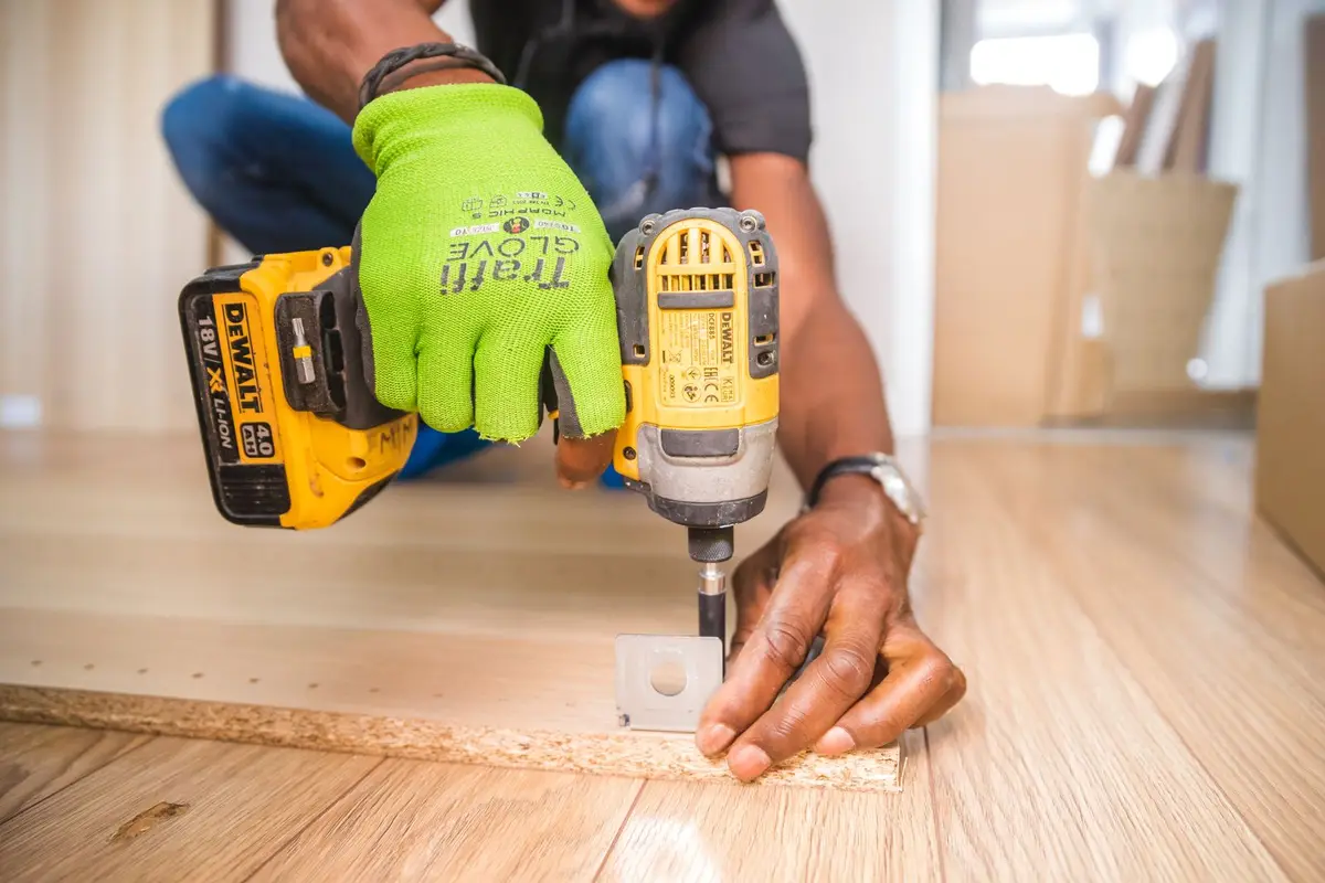 A carpenter using a drill on a wooden board.