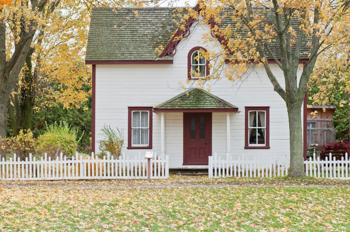 A white house with a garden fence in autumn light.
