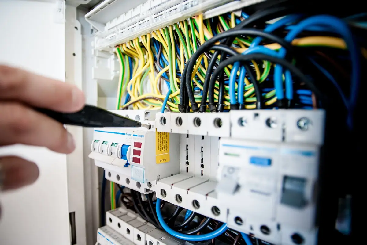 Hands testing circuits in an electrical consumer unit.
