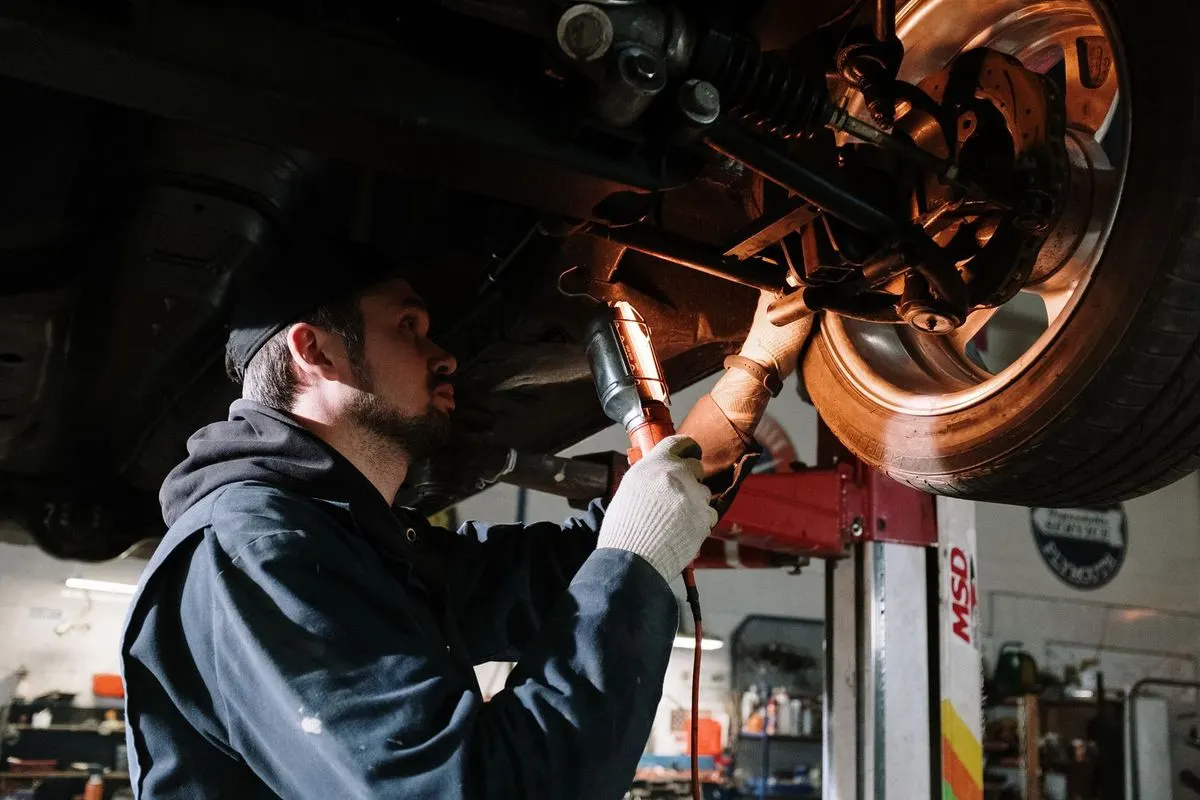 A mechanic working under a raised car.