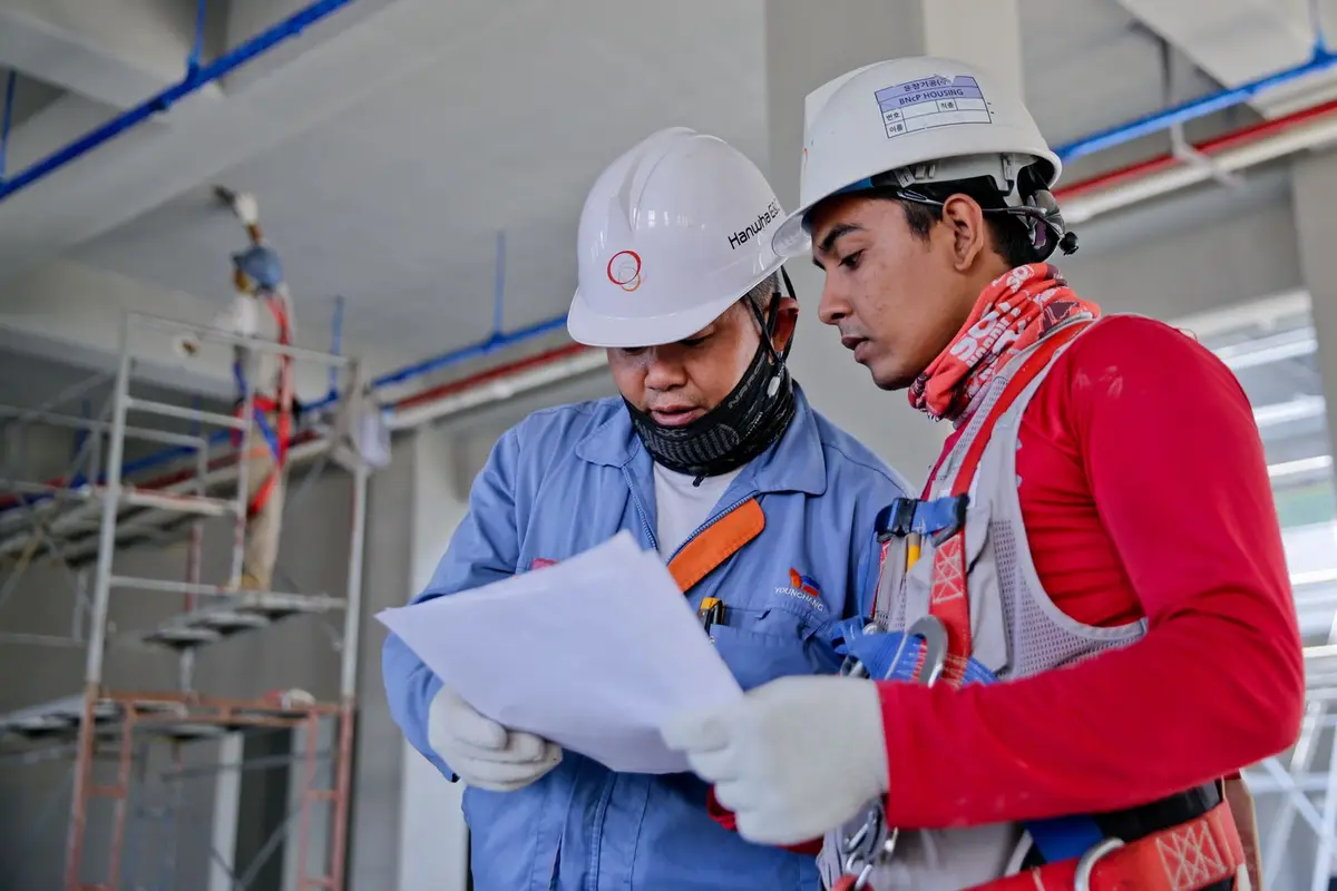 Two construction workers reviewing plans on site.