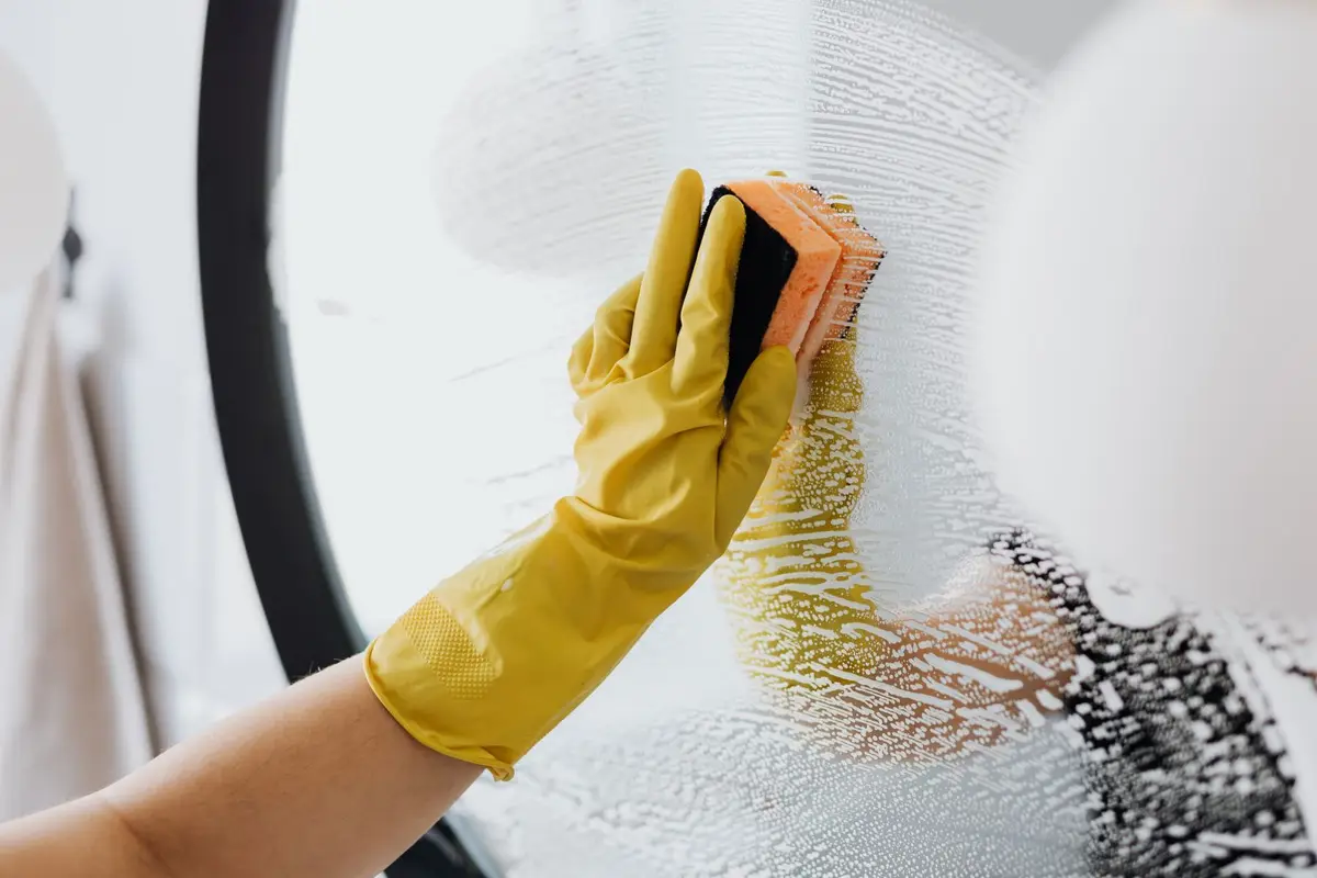 A gloved hand cleaning a window.