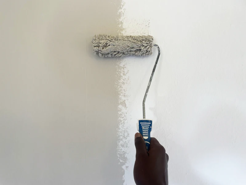 Paint roller applying white paint to a wall
