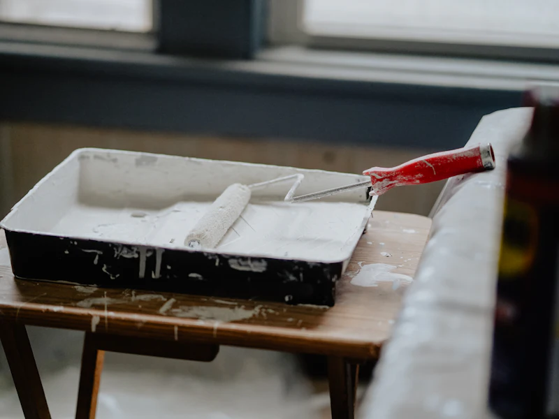 Paint roller in a tray of white paint
