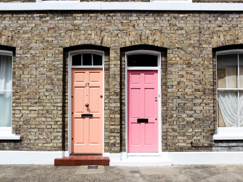 Pink painted front doors on a brick terrace